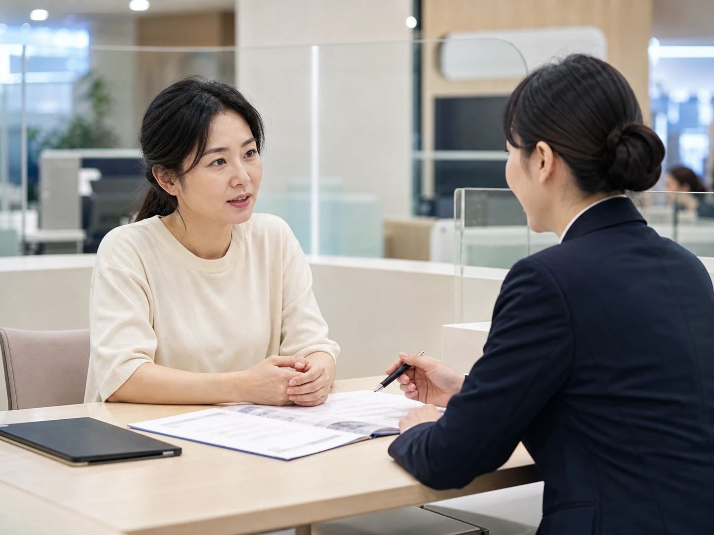 은행 창구에서 상담원과 대출 서류를 살펴보는 사업주